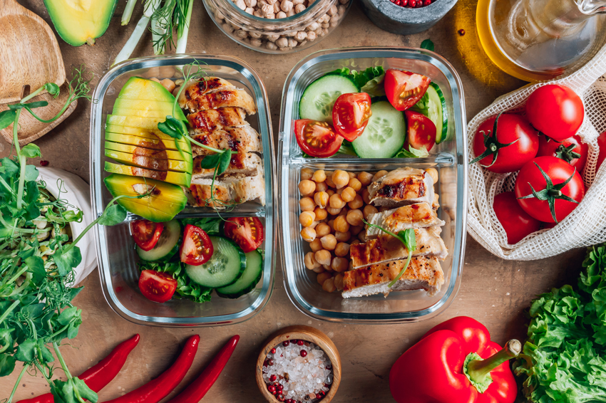 Healthy meal prep with containers filled with balanced ingredients and fresh vegetables around.