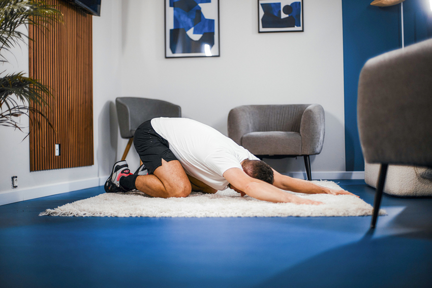 Man deep stretching kneeling on floor at home.